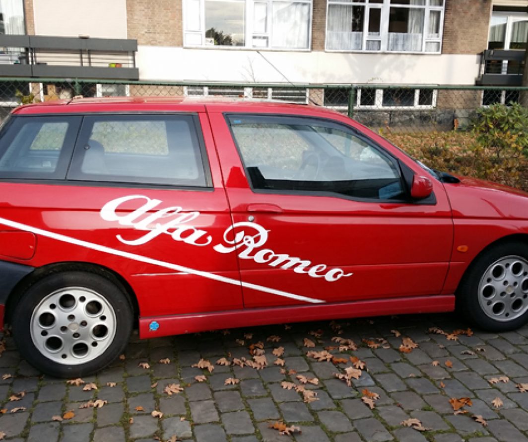 Rode Alfa Romeo met witte Alfa Romeo-belettering en een witte lijn over de zijkant